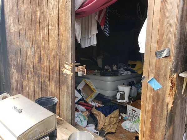 Poor living conditions including a blow up mattress on the floor of a wooden shed.