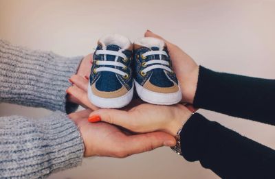 Two people holding tiny baby shoes together.