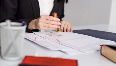 A person stamping documents at a desk in a professional setting.