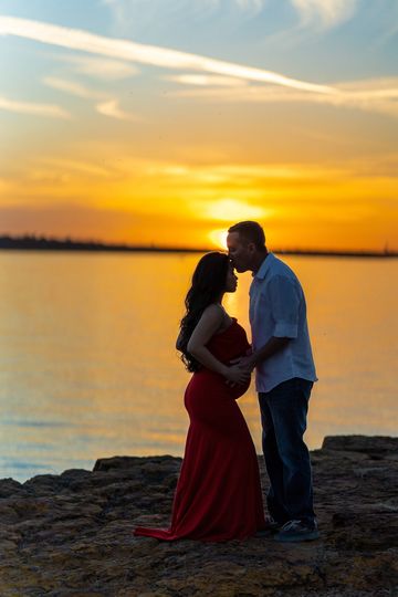 Couple sharing a tender moment at sunset by the water.