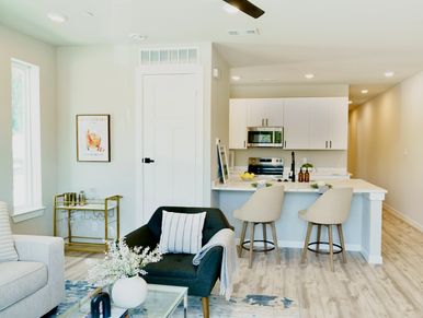 Modern living room with black and white furniture and a kitchen bar.