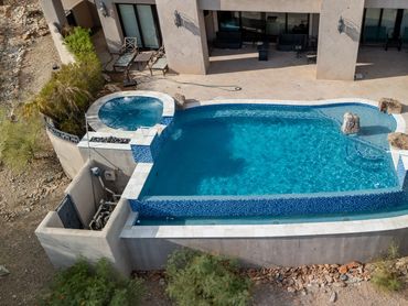 Aerial view of a completed pool and raised spa remodel with blue tile and clear water.