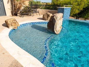 Finished pool baja shelf with decorative boulders, blue tile accents and newly finished pool surface