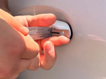 A person measuring a car door handle with a caliper.