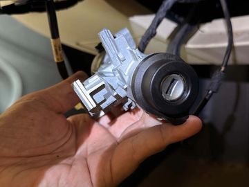 Hand holding a car ignition switch assembly.