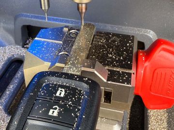A car key being cut by a precision milling machine.