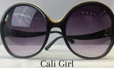 Round black sunglasses with gold accents and purple lenses labeled 'Cali Girl'.