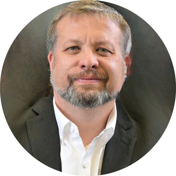 Man with beard in suit jacket and white shirt.