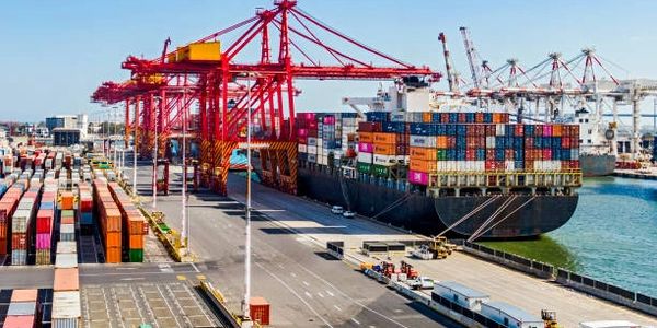 A busy container port with cranes loading cargo onto a large ship.