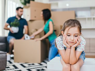 Sad child with moving boxes