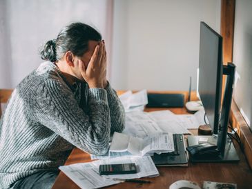 Person holding head while doing taxes