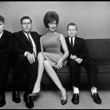 Black and white photo of a formally dressed family sitting on a couch.