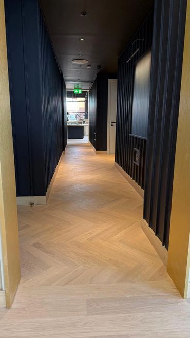 Modern hallway with light wood flooring and dark vertical paneled walls.