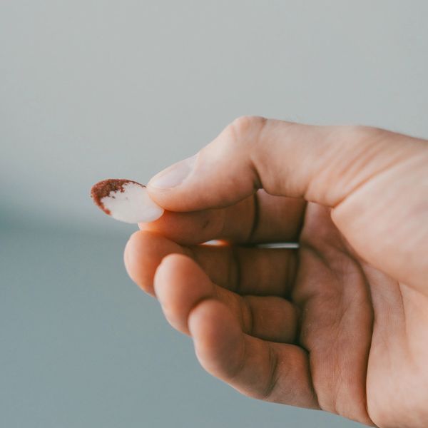 Hand holding a small, white object with a brown tip.