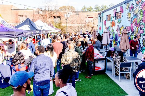 Crowd enjoying an outdoor event with colorful butterfly mural on the wall.