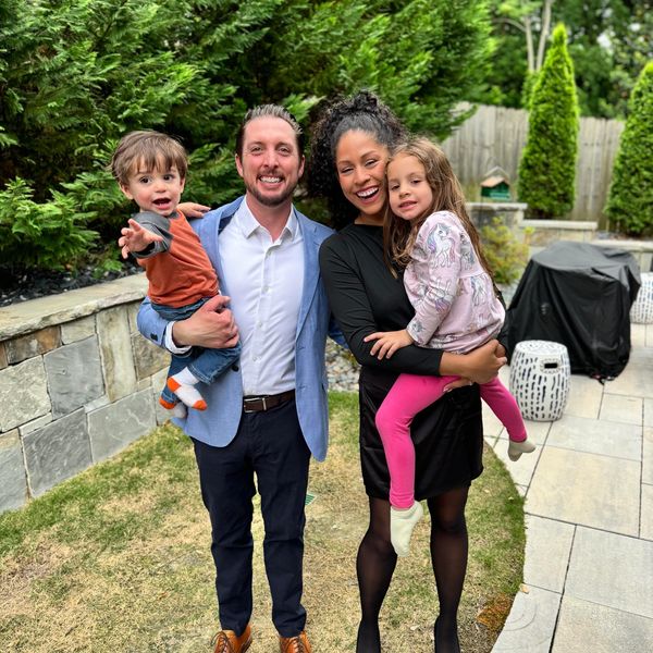 Happy family posing outside with two children in a garden.