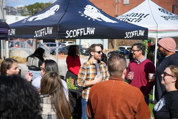 Group of people socializing under event tents on a sunny day.