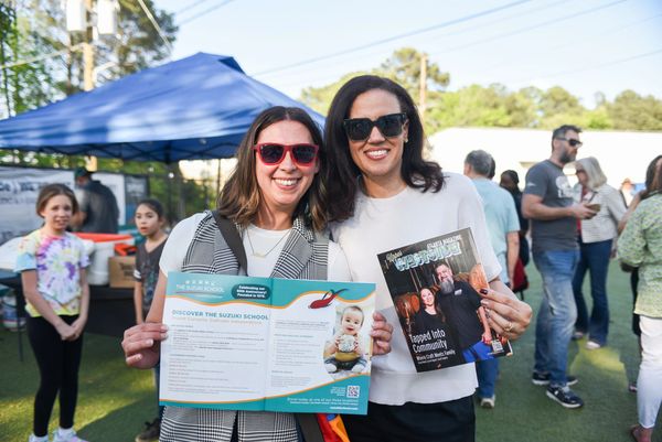 Two women holding brochures and smiling at an outdoor event.