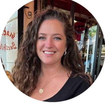 Smiling woman with curly hair at a cafe.