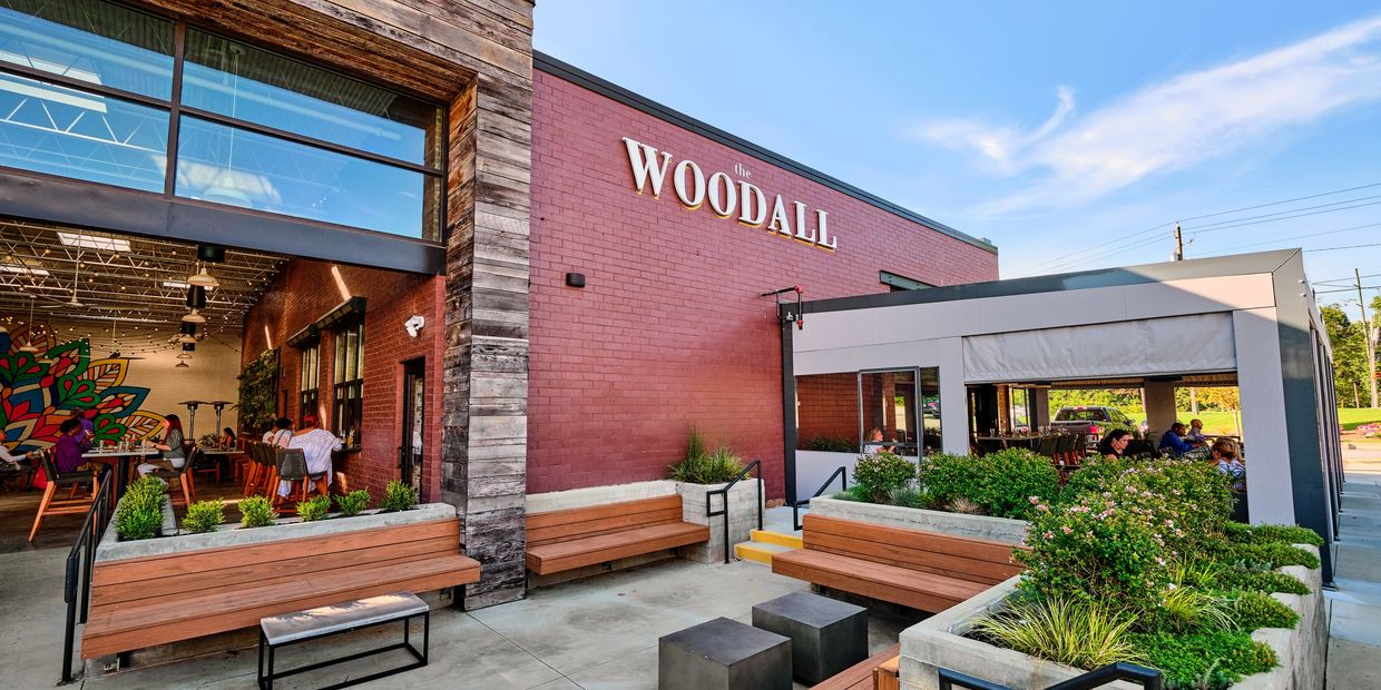 The Woodall restaurant with outdoor seating and greenery.