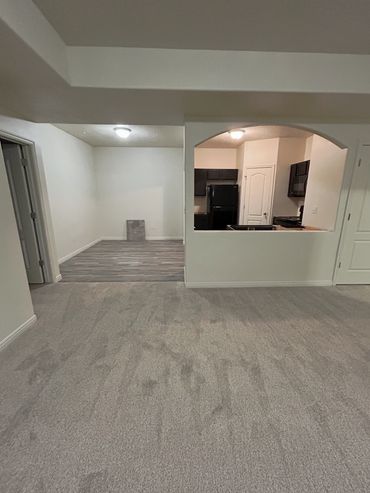 Carpeted living area with adjacent kitchen and dining space.