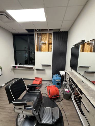 Empty barbershop chair in a room under renovation with drying equipment.