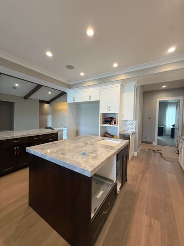 Modern kitchen with granite countertops and white cabinetry under recessed lighting.