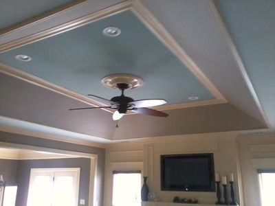 Decorative ceiling with a fan and recessed lights in a cozy living room.