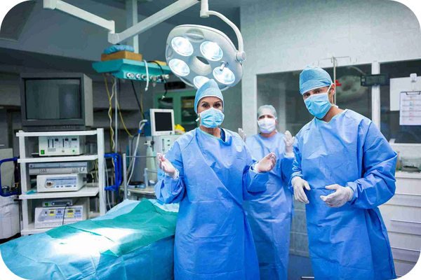 Surgeons in protective gear perform surgery in multiple theatres with air handling systems.