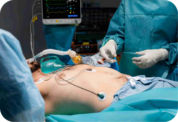 Patient in hospital gown undergoes endoscopy or colonoscopy in an operating room.
