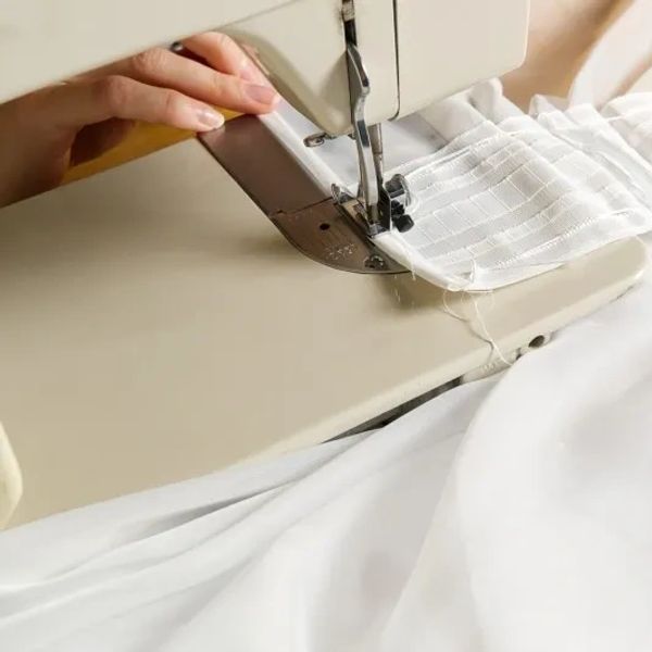 Stitching together a white curtain with a sewing machine