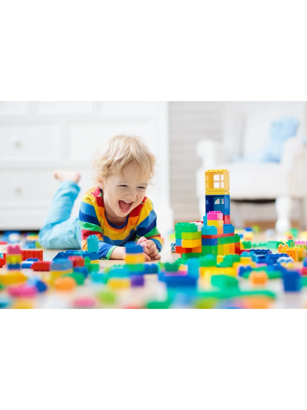 Child playing joyfully with colorful building blocks on the floor.