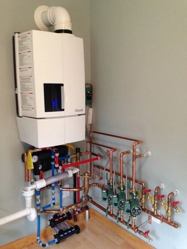 Wall-mounted boiler with an organized copper pipe and valve system.