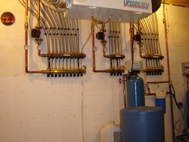 Complex plumbing system with multiple pipes and valves in a utility room.
