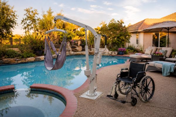 A wheelchair and pool lift by a residential pool.