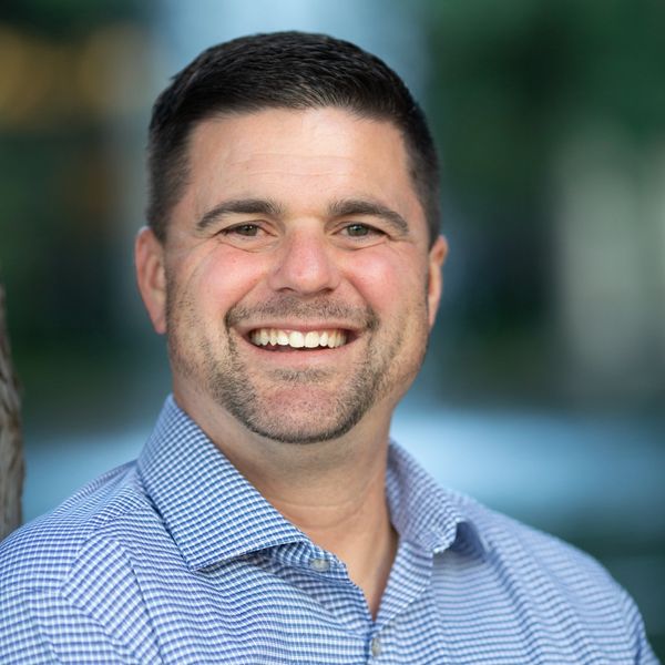 Smiling man in a blue checkered shirt.