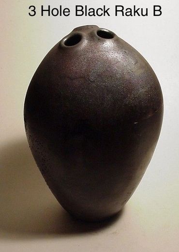 Three-hole black ceramic raku vessel.