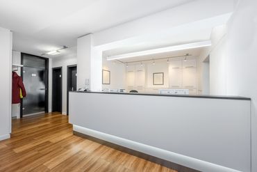 Modern reception area with white walls and wooden flooring.