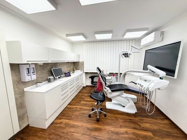 Modern dental clinic room with chair and equipment.