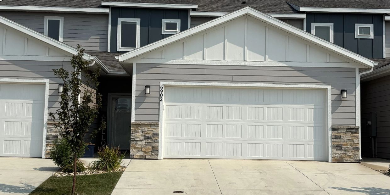 Modern townhouse with double garage and small landscaping.