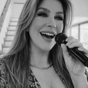 Woman joyfully singing into a microphone indoors.