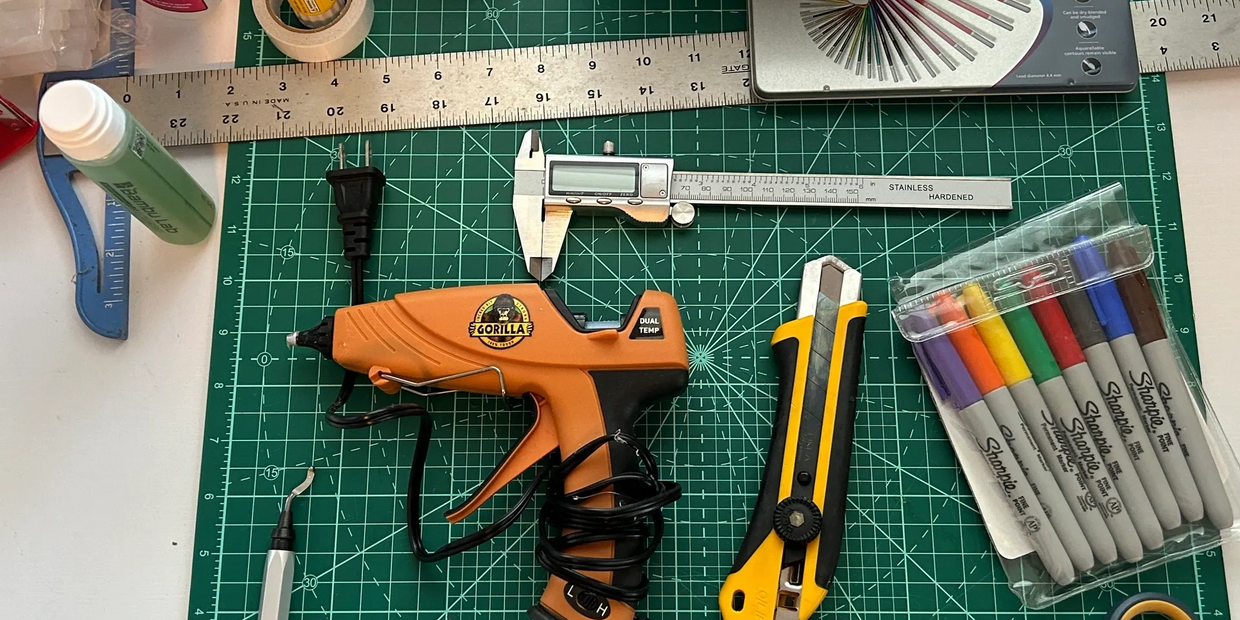 A variety of crafting tools and supplies neatly arranged on a green cutting mat.