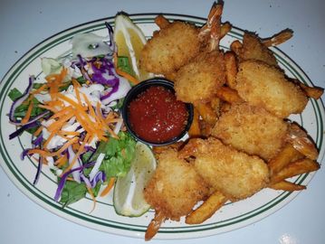 Plate of coconut shrimp with dipping sauce and fresh salad on the side.
