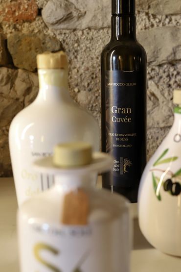 Bottles of Italian extra virgin olive oil against a rustic stone wall.