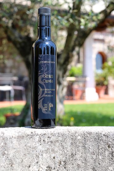 A bottle of Italian extra virgin olive oil on a stone surface outdoors.