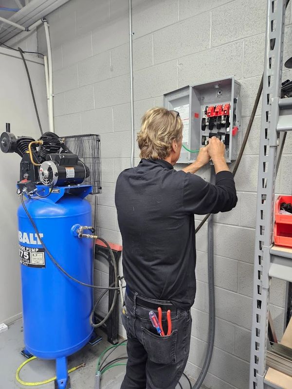 Man working on an electrical panel in a workshop.