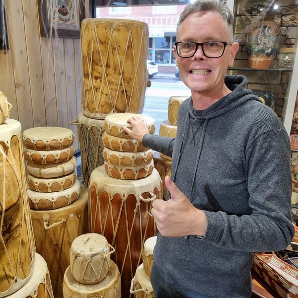 Man giving thumbs up next to wooden drums.