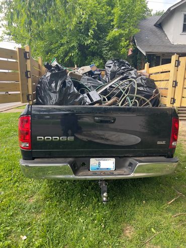 Black pickup truck with wood walls with junk in the truck's bed.
