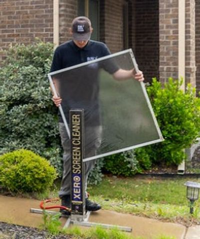 Person using a Xero Screen Cleaner outside a brick house.