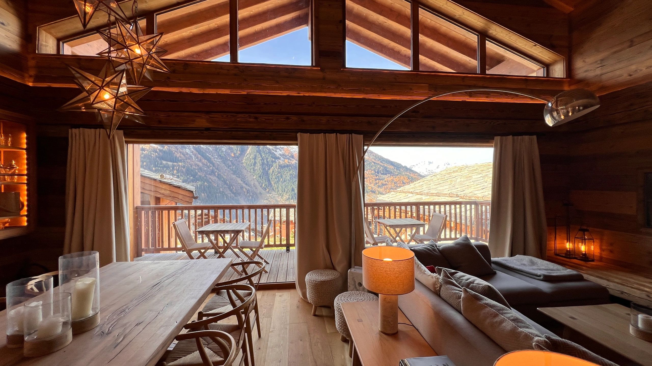 Cozy wooden cabin living area with mountain views and warm lighting.